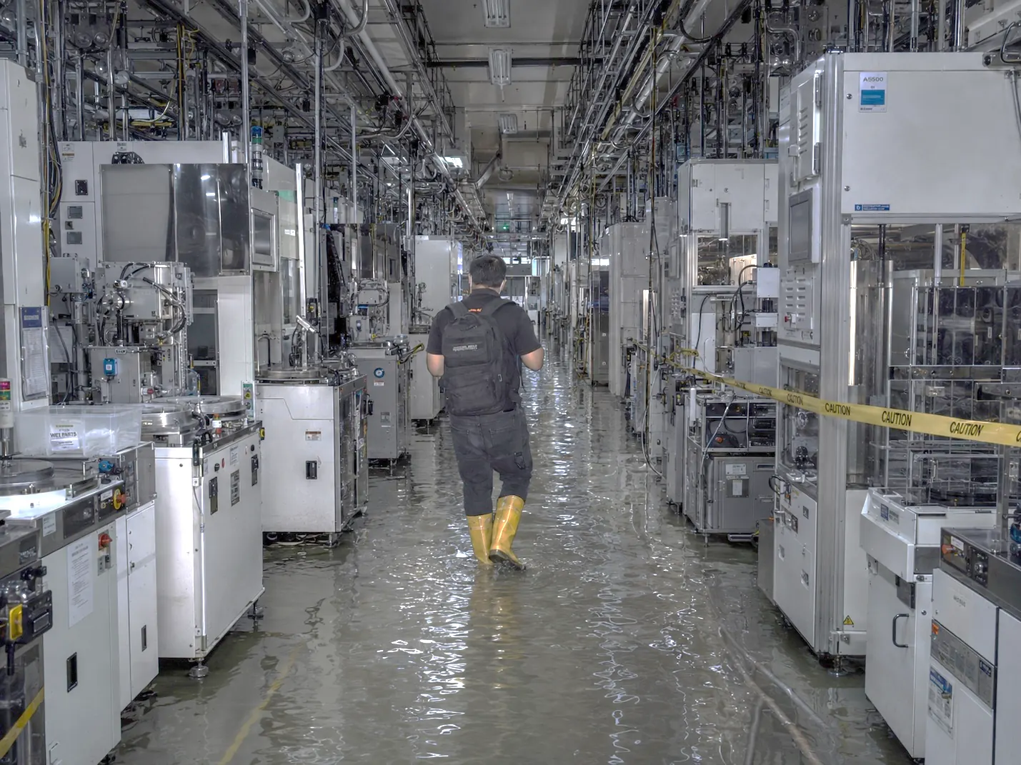 Engineer wading through floodwater in a semiconductor fabrication cleanroom